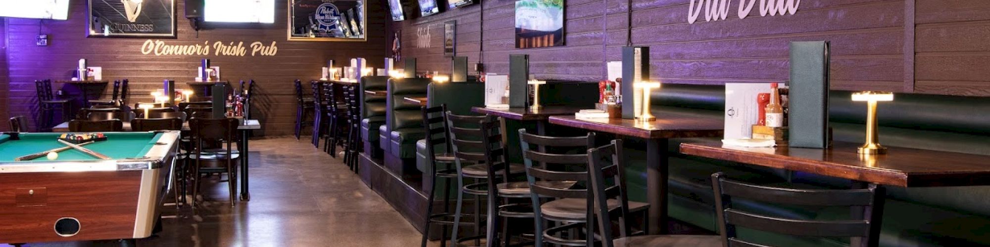 The image shows a sports bar with multiple TVs, high tables and chairs, a pool table, and décor with 