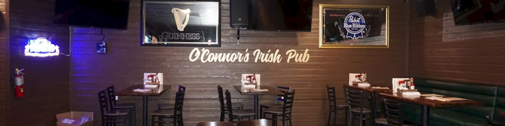 The image shows the interior of O'Connor's Irish Pub, with tables, chairs, bar stools, and a neon sign. Multiple TVs are mounted on the walls.